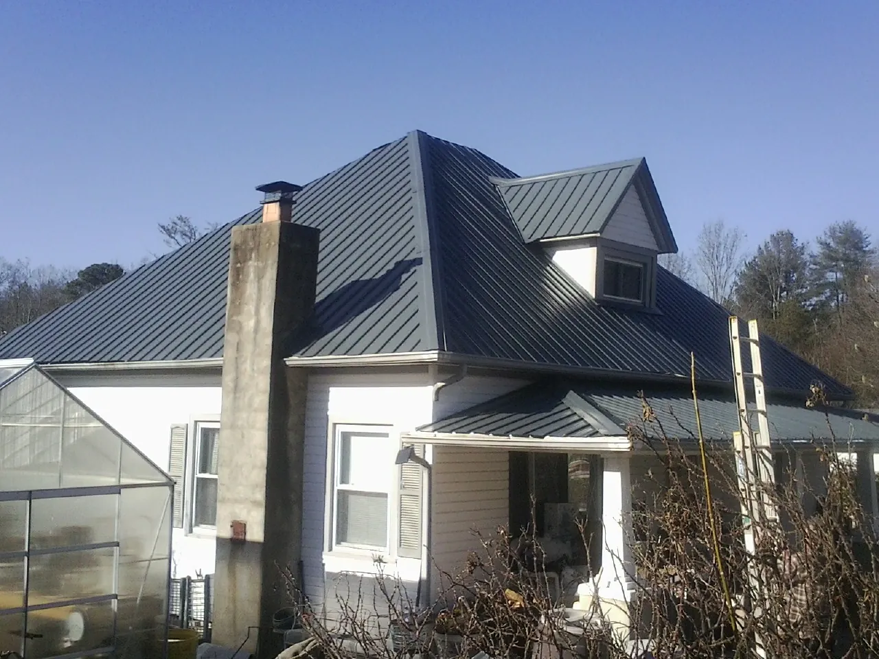 Dark blue standing seam metal roof on a white farmhouse with dormer — Slate & Tile Roof Repair by Roofing Brothers in Alpharetta