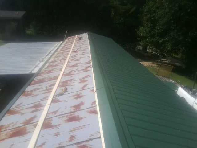 Old rusted panels beside newly installed green metal roofing — Wind Damage Roof Repair by Roofing Brothers in Alpharetta