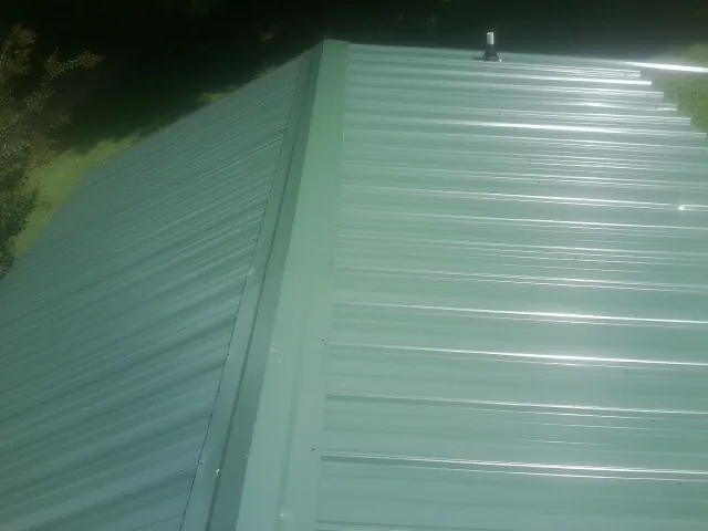 New green metal panels meeting at the ridge of a roof — Flat Roof Repair work by our crew in Alpharetta