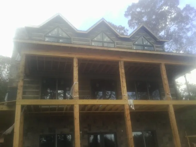 Dormers and porch framing on a large log home under construction — Roof Coating work by our crew in Alpharetta