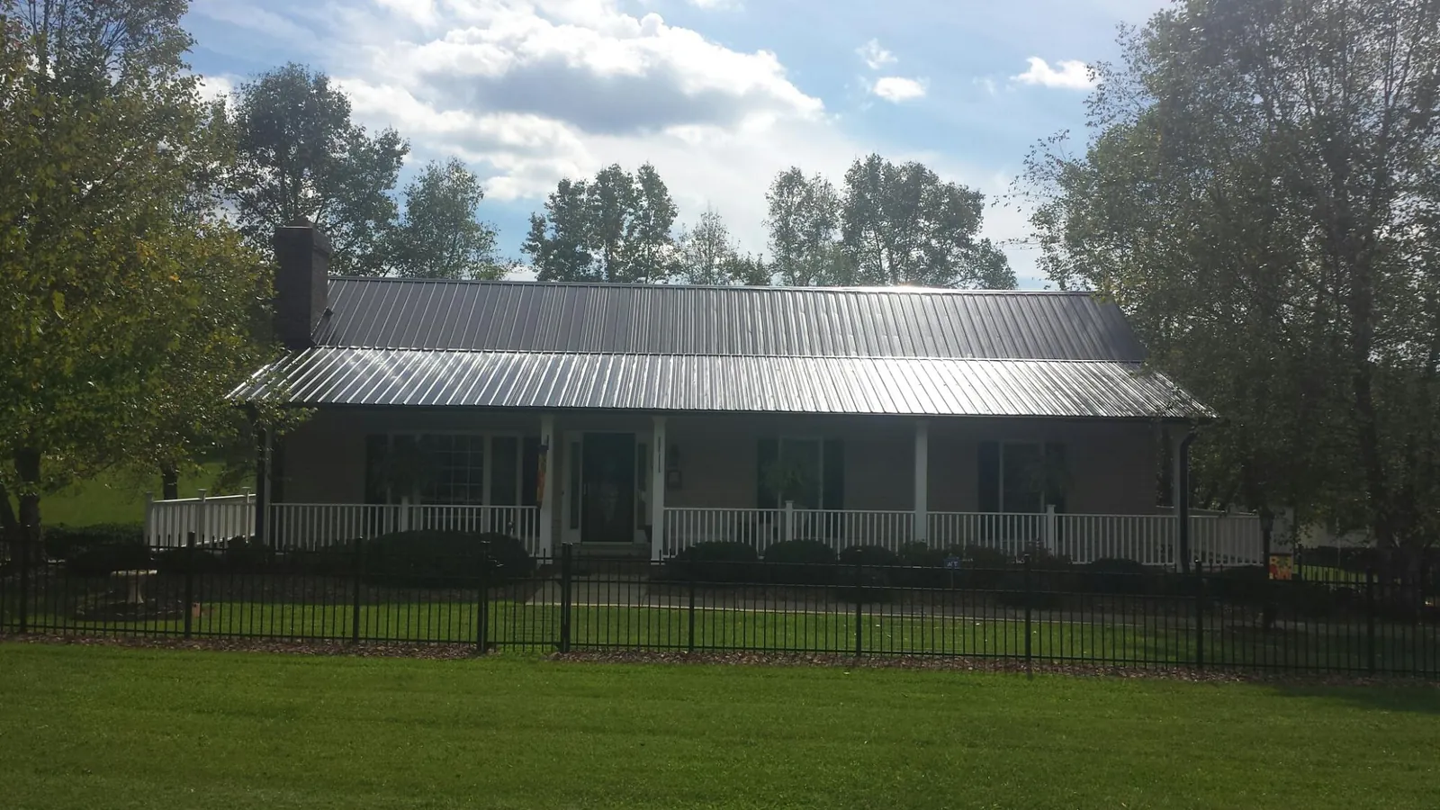 Gray metal roof on a brick ranch with a full width front porch — Gutter Guard Installation work by our crew in Alpharetta