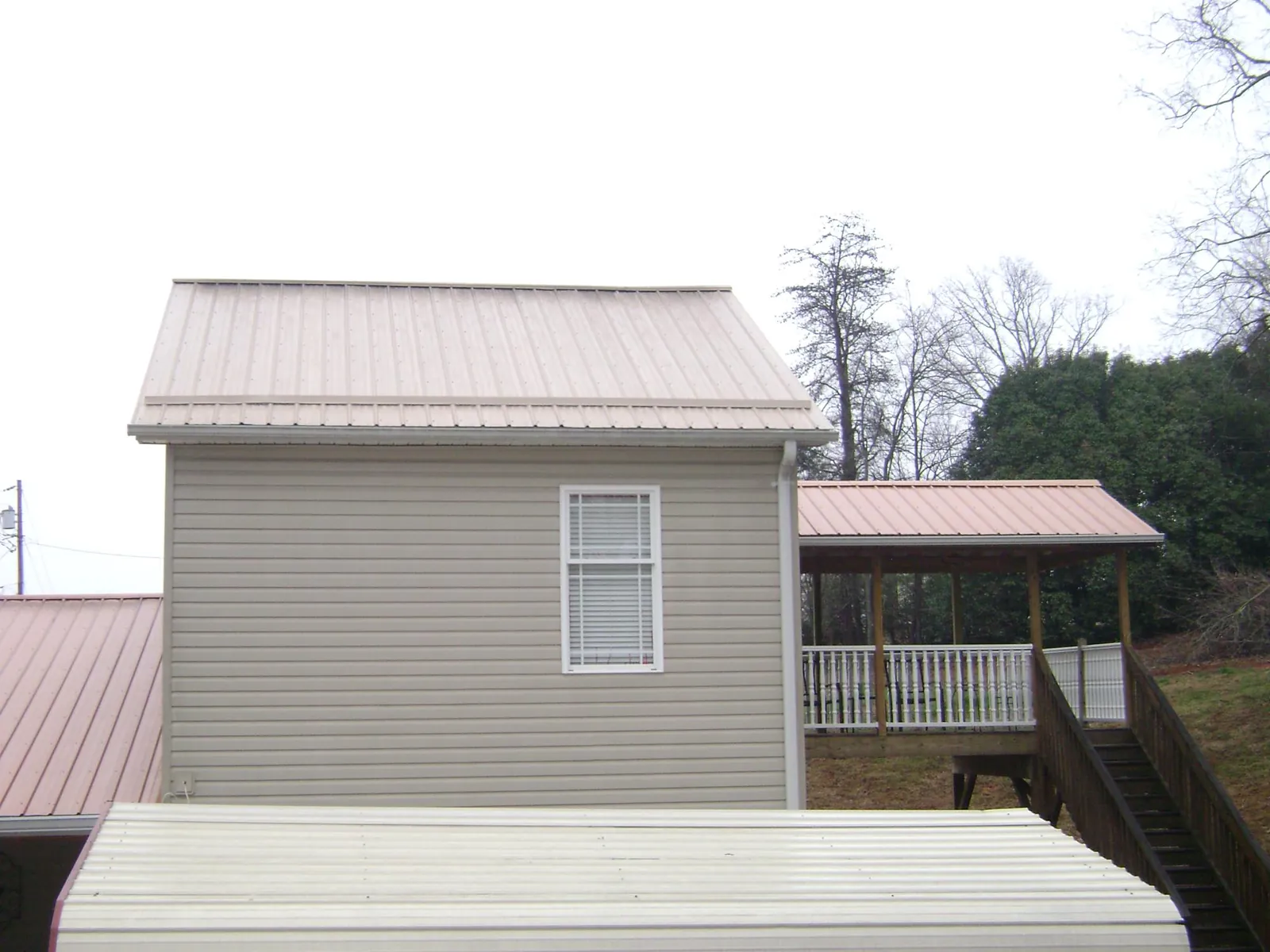 Tan metal roofs on a two story addition and attached porch, from a Roof Replacement job in Alpharetta