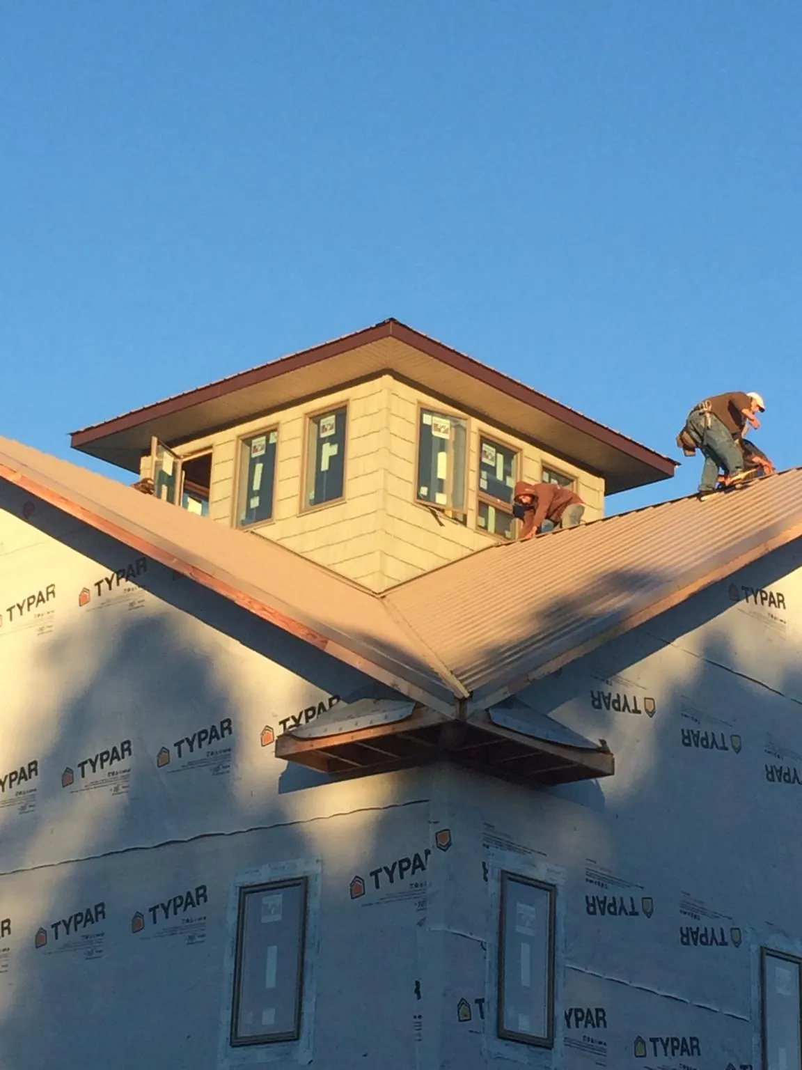 Roofers working around a rooftop cupola on a new metal roof at sunset — Roof Waterproofing in Alpharetta by Roofing Brothers